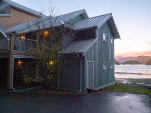 a large green building with a garage next to a house at Waterfront View of the Inlet, Short Walk to Town in Tofino