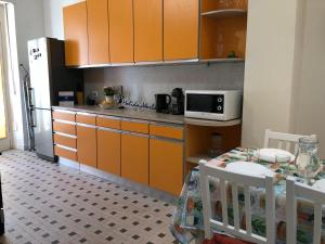 une cuisine avec des armoires orange, une table et un four micro-ondes dans l'établissement Casa di Max by Holiday World, à Turin