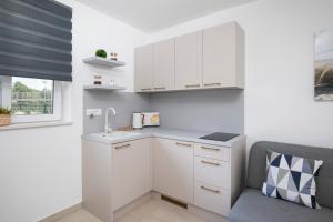 a small kitchen with white cabinets and a chair at Apartments and rooms Jakić in Medulin