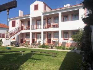 a large white building with chairs in the yard at Apartamentos São João in Horta