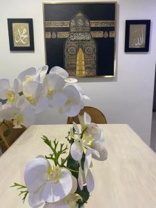 Homestay Mak Abah في كُوانتان: مزهرية من الزهور البيضاء تقف على طاولة