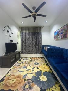 a living room with a blue couch and a ceiling fan at Homestay Mak Abah in Kuantan