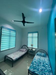 a room with two beds and a ceiling fan at Homestay Mak Abah in Kuantan