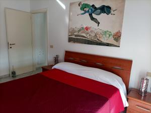 Un dormitorio con una cama roja y una pintura en la pared en Appartamento Verde Salvia, en Pescara