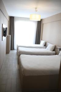 a hotel room with three beds and a window at Cinas Hotel in Eskisehir