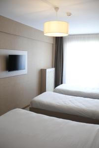 a hotel room with two beds and a flat screen tv at Cinas Hotel in Eskisehir