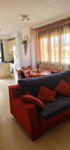 een woonkamer met een rode bank en een tafel bij Marvic Llanes in Posada de Llanes