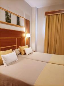 um quarto de hotel com duas camas e uma janela em Hotel Carmen em La Carlota