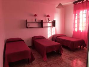 um quarto com duas camas vermelhas e uma janela em Trilocale Serra Li Lioni - Sassari em Sassari