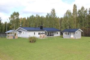 ein weißes Haus mit einem großen Hof mit einem Haus in der Unterkunft Villa Kupsala , LaatuLomat in Juva