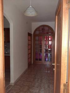 um corredor com uma porta e uma cozinha com prateleiras de vinho em Trilocale Serra Li Lioni - Sassari em Sassari