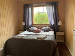1 dormitorio con 1 cama con 2 almohadas y ventana en Villa Kupsala , LaatuLomat, en Juva