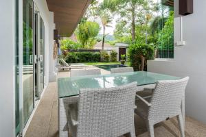 um pátio com uma mesa de vidro e cadeiras em Balinese Style 3BR Villa Morning Forest, Nai Harn em Rawai Beach