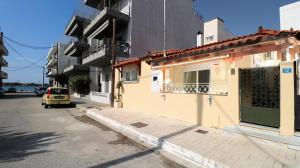 a small yellow car parked next to a building at Family beach house near airport in Artemida