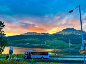 een bus geparkeerd naast een meer met een zonsondergang bij Rowantreebank Bed and Breakfast in Arrochar