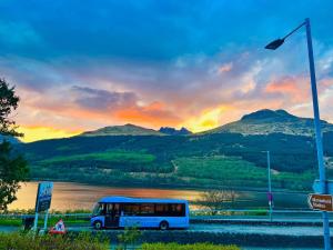 un autobus parcheggiato vicino a un lago con un tramonto di Rowantreebank Bed and Breakfast ad Arrochar