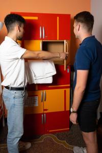 two men are looking into a red cabinet at Manena Hostel Genova in Genova