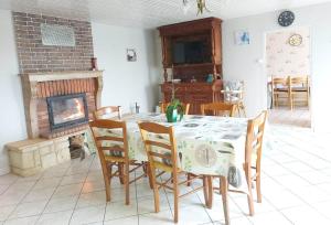 ein Esszimmer mit einem Tisch, Stühlen und einem Kamin in der Unterkunft La-Haut, gite-maison de vacances in Poinson-lès-Fays