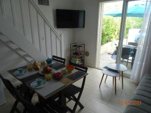 une salle à manger avec une table, des chaises et une télévision dans l'établissement Maison cocooning à 1km de la mer, à Saint-Cyprien