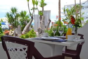 een witte tafel met stoelen en wijnglazen op een balkon bij Apartamentos Garden Atlantis en Club Atlantis in Adeje