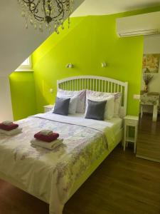 a bedroom with a white bed with a green wall at MKR Family Room in Zagreb