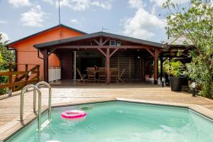 a house with a swimming pool and a wooden deck at La Villa Holiday, 10 personnes, piscine patio bar terrasse in Sainte-Rose