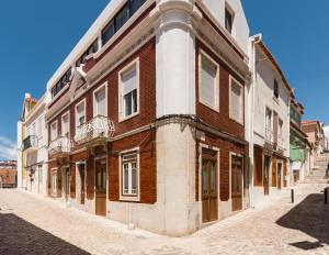 a large brick building on a cobblestone street at Casa do Tio Farinha by RNvillage in Sesimbra