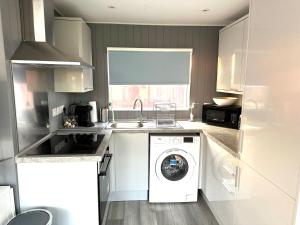 a kitchen with a washing machine and a sink at Beautiful Chalet, 18 Cordova, Selsey Country Club in Selsey