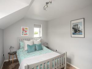 a white bedroom with a bed with blue pillows at The Old Coal Yard in Cemaes Bay
