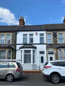 two cars parked in front of a white house at Private double room in our Cardiff Home in Cardiff