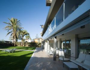 eine Terrasse eines Hauses mit weißen Stühlen und Palmen in der Unterkunft Las Barcas in San Agustín