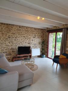 a living room with a stone wall and a television at Le Domaine de la petite chèvre in Ploumagoar