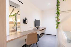 Zimmer mit einem Schreibtisch, einem TV und einem Spiegel in der Unterkunft Hotel NuVe in Singapur