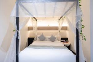 um quarto com uma cama de dossel com lençóis e almofadas brancos em Hotel NuVe em Singapura