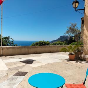 a blue table and chairs on a patio with the ocean at Joli deux pièces vieux village de Roquebrune-Cap-Martin in Roquebrune-Cap-Martin