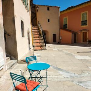 dwa krzesła i stół przed budynkiem w obiekcie Joli deux pièces vieux village de Roquebrune-Cap-Martin w mieście Roquebrune-Cap-Martin