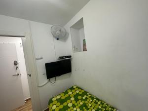 Habitación pequeña con cama verde y ventilador. en El BUHO DE CORDOBA, en Córdoba