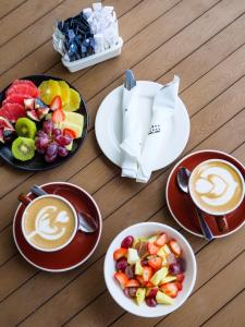 uma mesa com pratos de frutas e chávenas de café em Vineyard Hotel em Cidade do Cabo