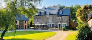 a large stone building with a blue roof at Le Manoir des Haies SPA in Les Champs-Géraux