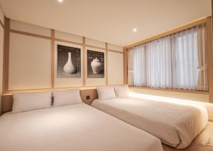 two beds sitting next to each other in a room at UH Suite Central Seoul in Seoul