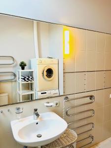 ein Badezimmer mit einem Waschbecken und einer Waschmaschine in der Unterkunft Super Apartment Old town in Klaipėda