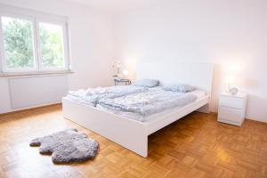 ein weißes Schlafzimmer mit einem weißen Bett und einem Fenster in der Unterkunft Lions Apartments - Erholung und Vergnügen in Bad Tatzmannsdorf in Jormannsdorf