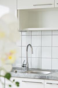 eine Küche mit einem Waschbecken und weiß gefliesten Wänden in der Unterkunft Lions Apartments - Erholung und Vergnügen in Bad Tatzmannsdorf in Jormannsdorf