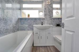 een witte badkamer met een wastafel en een bad bij Cosy home by the sea in Cleethorpes