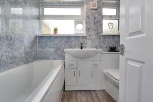 y baño blanco con lavabo y bañera. en Cosy home by the sea en Cleethorpes