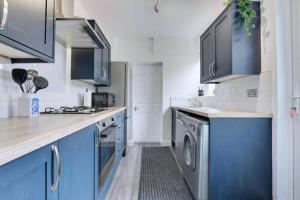 a kitchen with blue cabinets and a washer and dryer at Cosy home by the sea in Cleethorpes