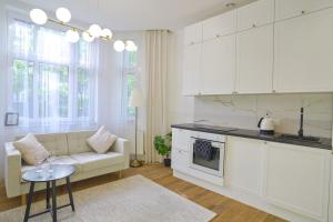 cocina y sala de estar con armarios blancos y sofá en Apartament Mieszka I - Śródmieście, en Gorzów Wielkopolski