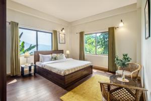 a bedroom with a bed and a large window at StayVista's Tree Tops & Tea Trails - Mountain-View Villa Amidst Tea Plantation with Telescope & Gazebo in Darjeeling