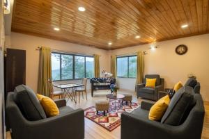 a living room with two couches and a dining room at StayVista's Tree Tops & Tea Trails - Mountain-View Villa Amidst Tea Plantation with Telescope & Gazebo in Darjeeling
