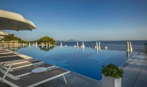 a pool with chairs and an umbrella and the ocean at Sanpier Apartments in Veli Lošinj